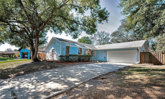 ranch-style house featuring an attached garage, fence, and driveway