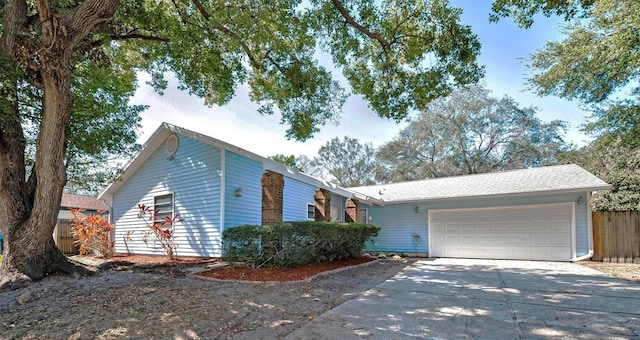 view of front of home with a garage, concrete driveway, and fence