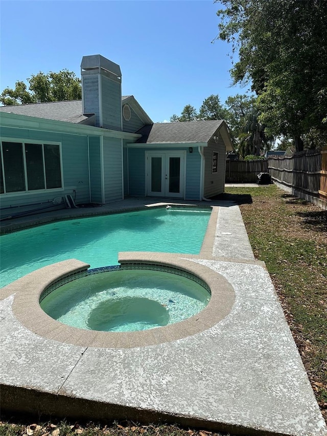 view of pool with french doors, a pool with connected hot tub, and fence