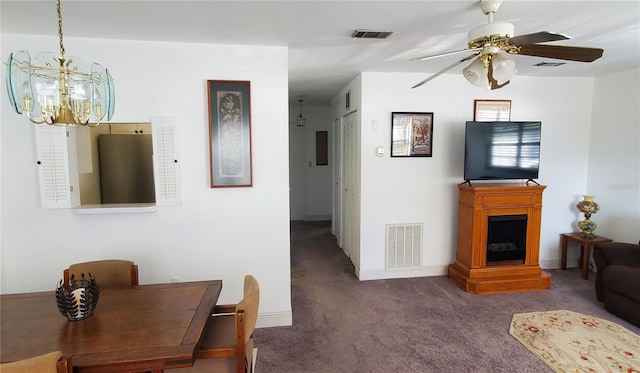 carpeted living area featuring ceiling fan with notable chandelier, a fireplace, and visible vents