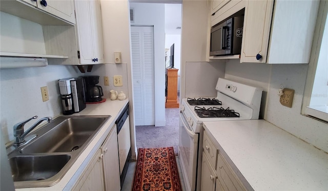 kitchen featuring white gas stove, a sink, white cabinets, light countertops, and dishwasher