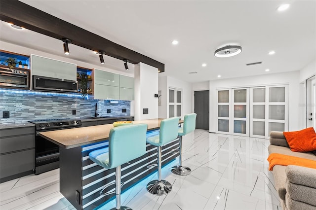 kitchen featuring electric range, a sink, marble finish floor, backsplash, and stainless steel microwave