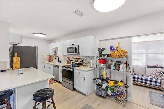 kitchen with appliances with stainless steel finishes, a breakfast bar, sink, and white cabinets