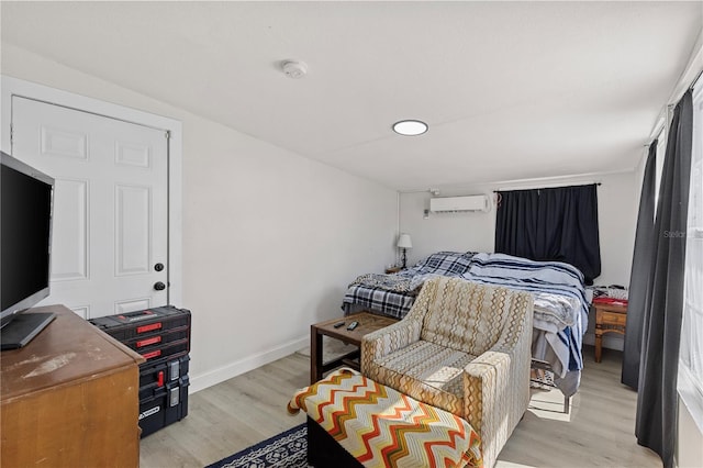 bedroom with an AC wall unit and light wood-type flooring