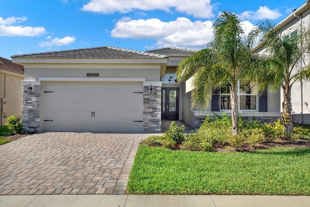 view of front of house featuring stone siding, stucco siding, decorative driveway, and a garage