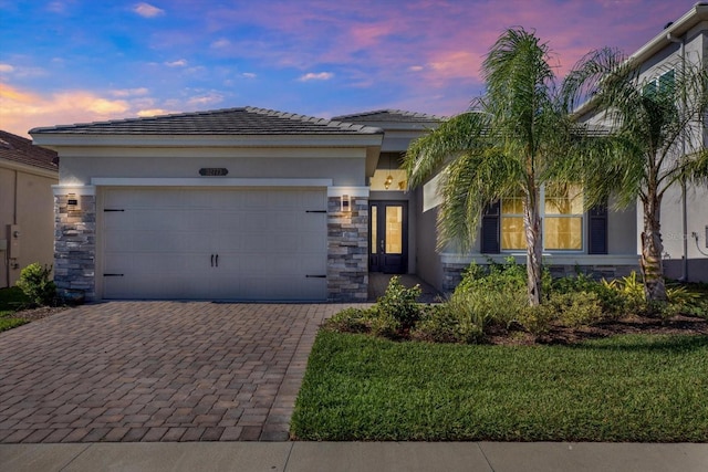 view of front of house featuring decorative driveway, stone siding, and stucco siding