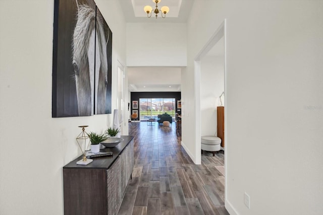 hallway with a notable chandelier, baseboards, and dark wood-type flooring