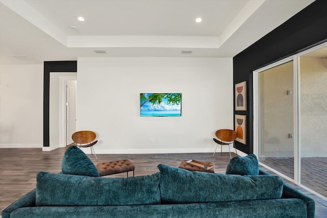 living area with a tray ceiling, wood finished floors, and baseboards