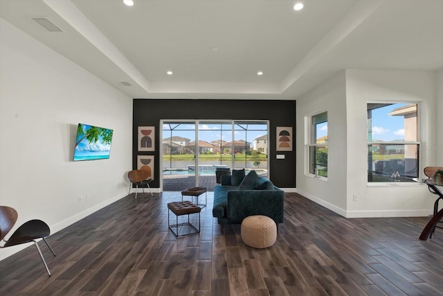 living room featuring wood finished floors, a tray ceiling, and a sunroom