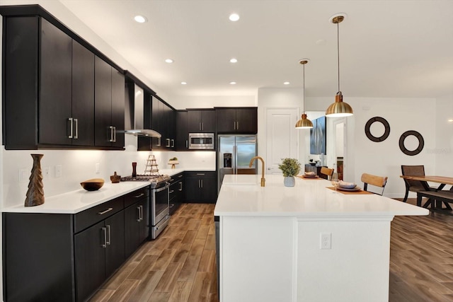 kitchen featuring light wood-style flooring, a sink, light countertops, appliances with stainless steel finishes, and decorative light fixtures