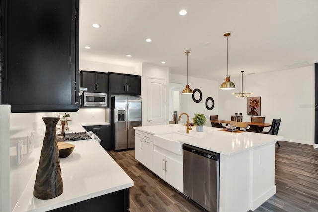 kitchen with a sink, light countertops, dark wood-type flooring, appliances with stainless steel finishes, and dark cabinets