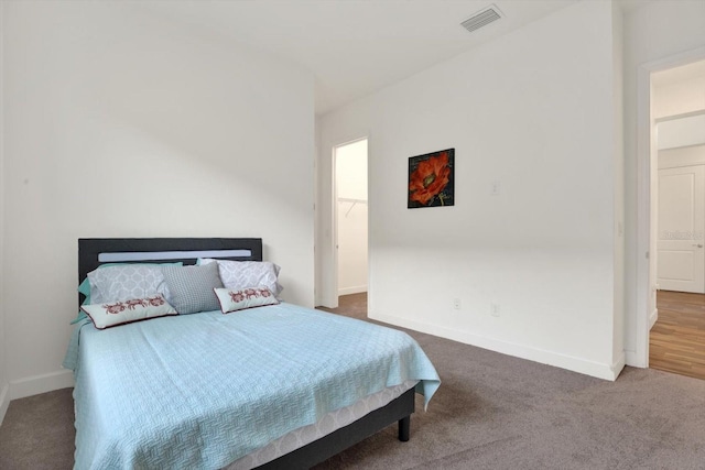 bedroom with visible vents, carpet floors, baseboards, and a walk in closet