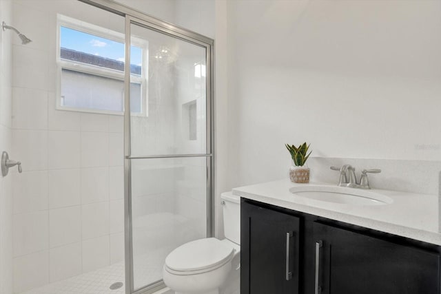 bathroom featuring toilet, a stall shower, and vanity