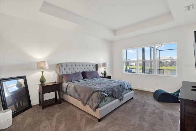 carpeted bedroom featuring a raised ceiling, baseboards, and visible vents