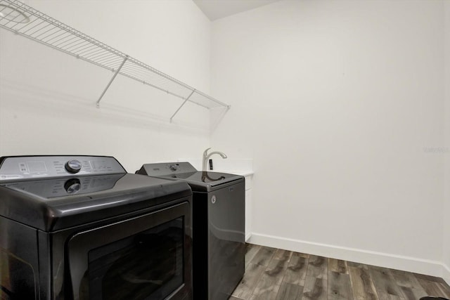 washroom with washer and dryer, laundry area, wood finished floors, and baseboards