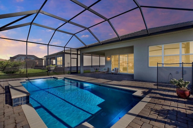 pool at dusk with a patio, an outdoor pool, and a lanai