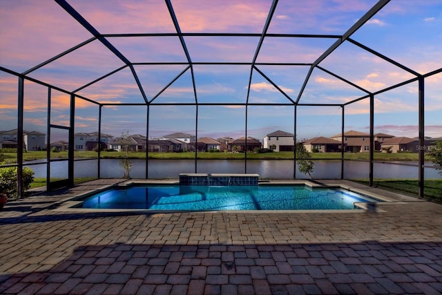 pool at dusk with a water view, glass enclosure, a residential view, an outdoor pool, and a patio area