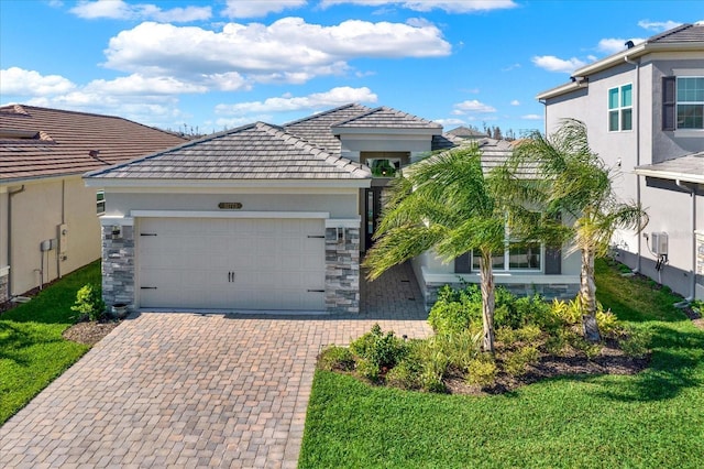 view of front of home featuring decorative driveway, a tile roof, an attached garage, and stucco siding