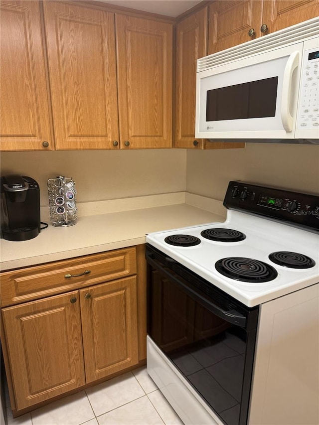 14132 89th Ave, Seminole, FL 33776 - kitchen featuring brown cabinets, range with electric cooktop, light countertops, and white microwave