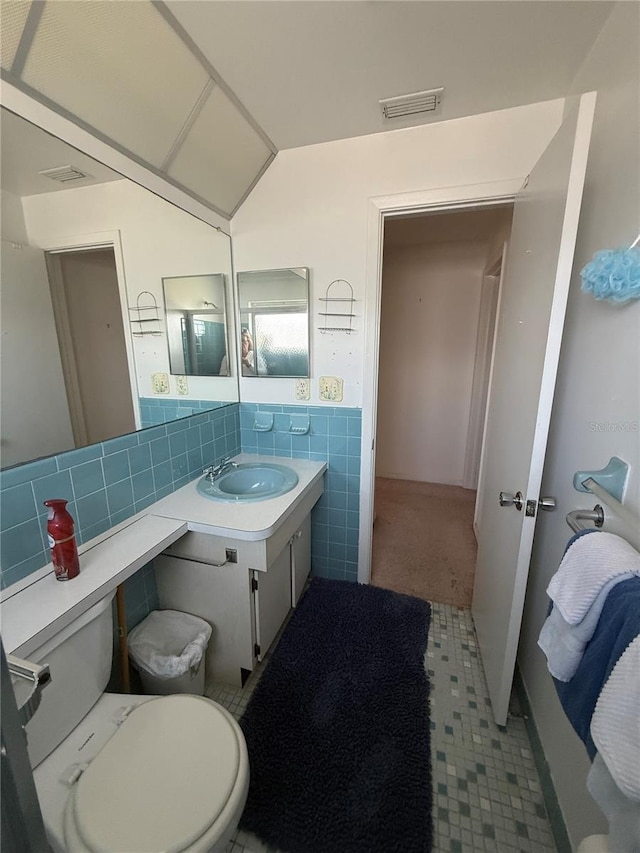 14132 89th Ave, Seminole, FL 33776 - bathroom featuring tile walls, visible vents, toilet, vaulted ceiling, and vanity