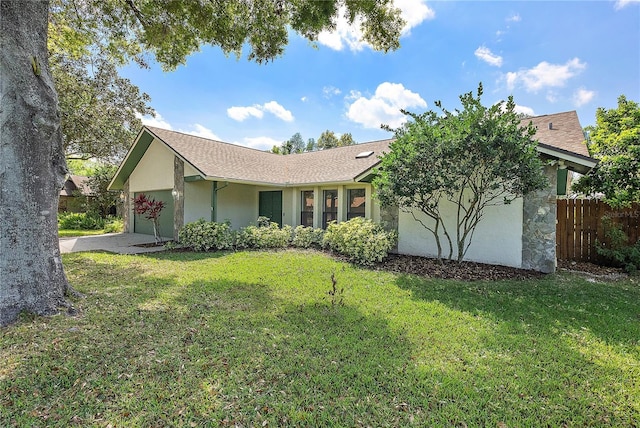 ranch-style house featuring driveway, a front yard, an attached garage, and fence