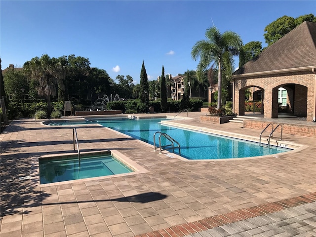 view of pool with a hot tub and a patio