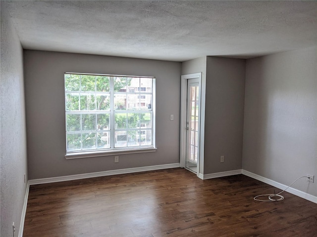 spare room featuring dark hardwood / wood-style floors and a textured ceiling