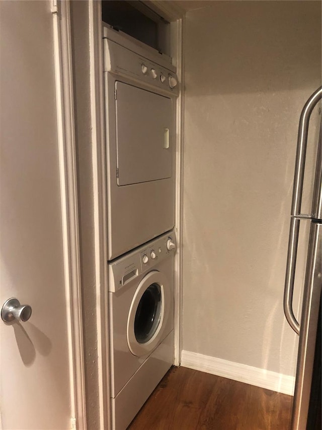 laundry room with stacked washing maching and dryer and dark hardwood / wood-style flooring