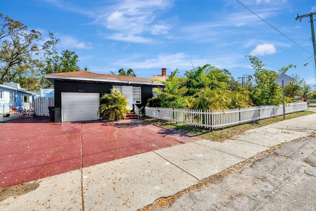 1011 W Columbus Dr, Tampa, FL 33602 - ranch-style house with concrete driveway, a fenced front yard, and a garage