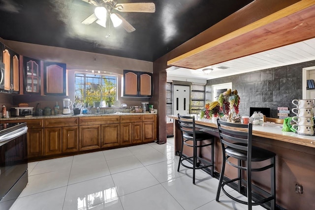 1011 W Columbus Dr, Tampa, FL 33602 - kitchen featuring glass insert cabinets, brown cabinetry, range with electric stovetop, light countertops, and a ceiling fan