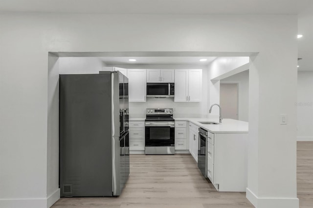 kitchen featuring appliances with stainless steel finishes, sink, white cabinets, and light hardwood / wood-style floors