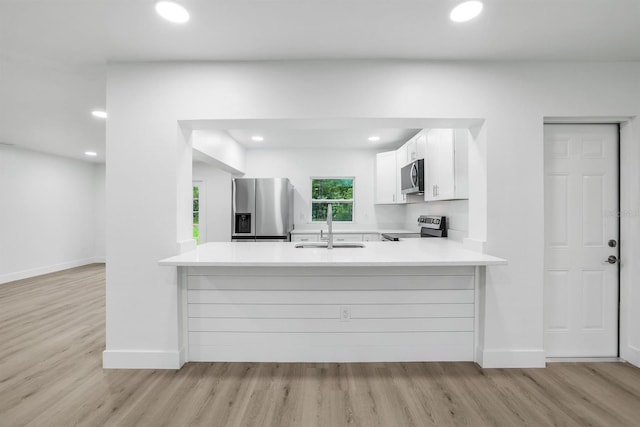 kitchen with stainless steel appliances, sink, white cabinets, and kitchen peninsula