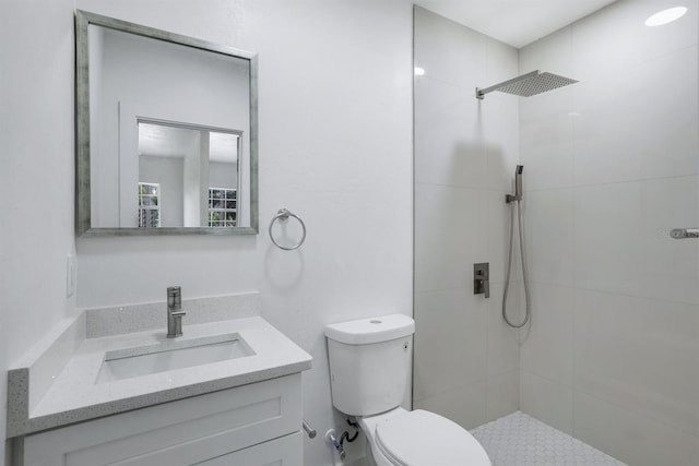 bathroom featuring vanity, a tile shower, and toilet