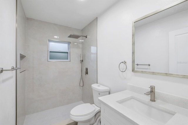 bathroom featuring vanity, toilet, and a tile shower