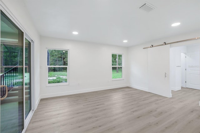 empty room featuring a barn door and light hardwood / wood-style floors