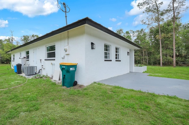 view of side of home featuring a lawn, central AC unit, and a patio area