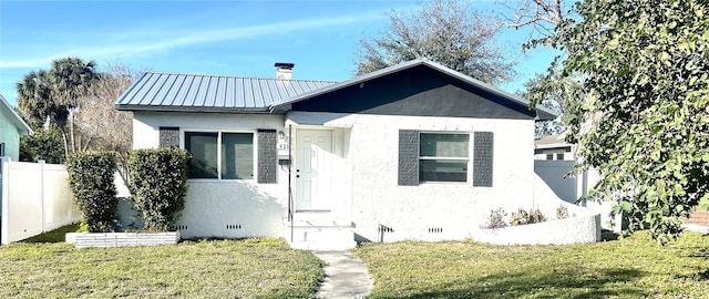 bungalow-style home with a front lawn, fence, stucco siding, metal roof, and crawl space