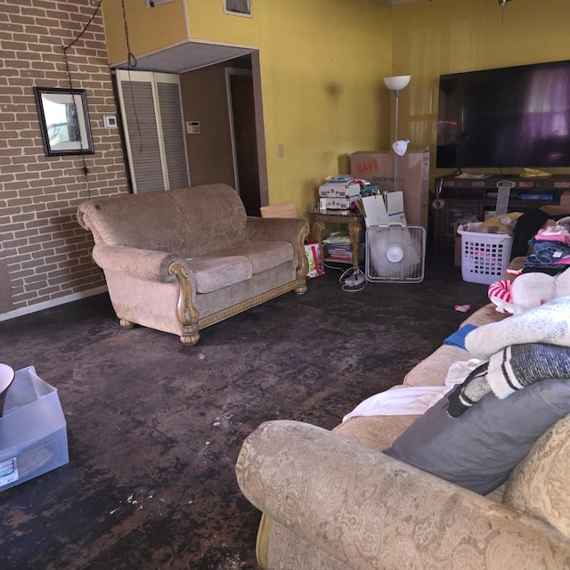 living room featuring concrete flooring, brick wall, and visible vents