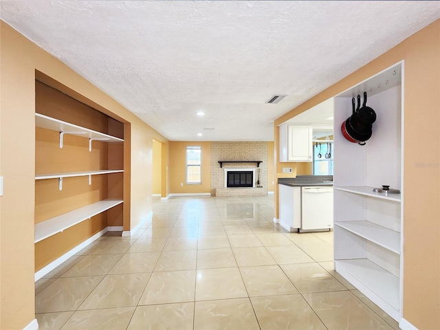 unfurnished living room with baseboards, visible vents, a textured ceiling, a fireplace, and light tile patterned flooring