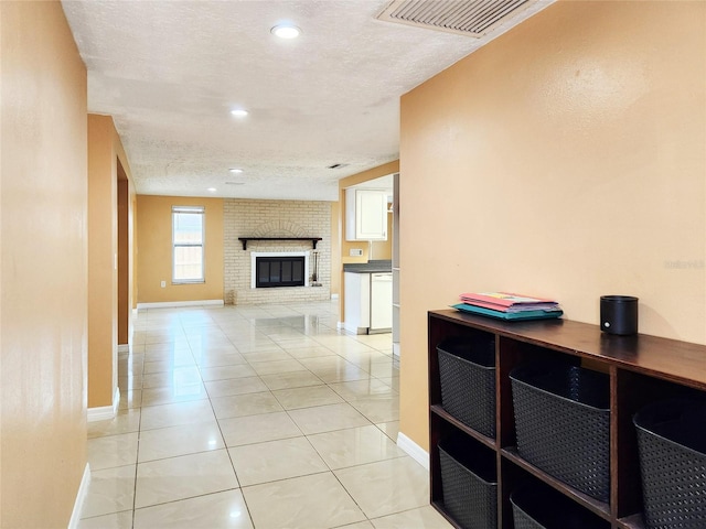 corridor featuring light tile patterned floors, a textured ceiling, recessed lighting, visible vents, and baseboards