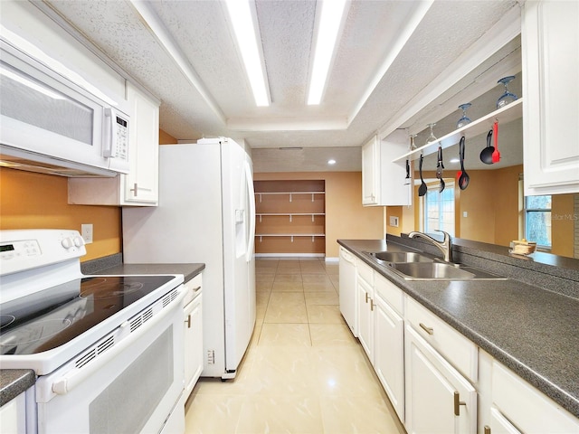 kitchen featuring dark countertops, white appliances, and white cabinetry