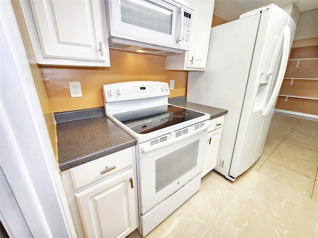 kitchen featuring dark countertops, white appliances, white cabinets, and light tile patterned flooring