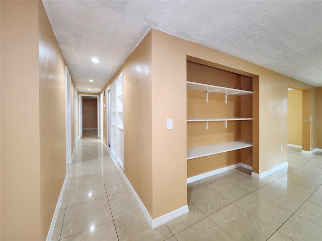 hallway with tile patterned flooring and a textured ceiling