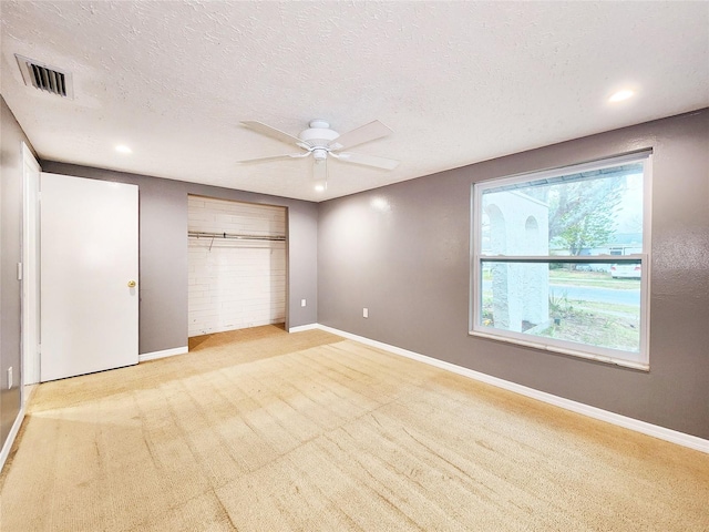 unfurnished bedroom with a ceiling fan, light colored carpet, visible vents, and baseboards