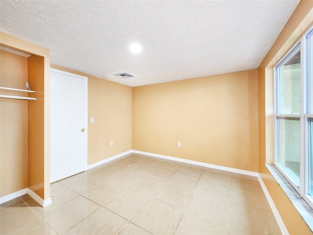 unfurnished bedroom featuring visible vents, a textured ceiling, and baseboards