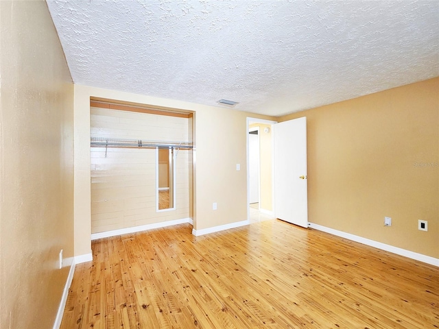 spare room featuring wood-type flooring, visible vents, and baseboards