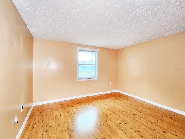 unfurnished room featuring a textured ceiling, wood-type flooring, and baseboards