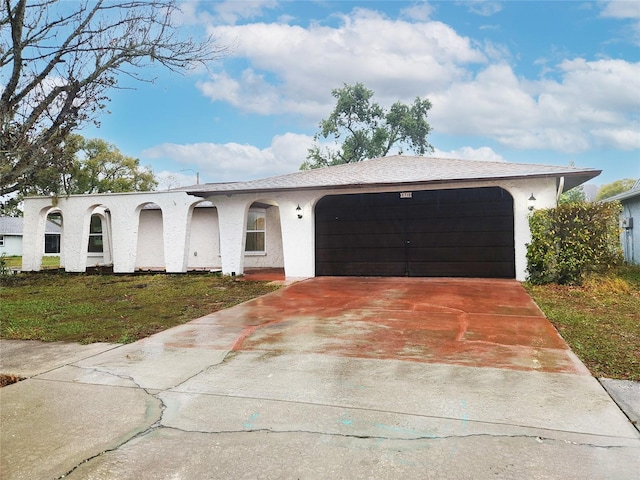 view of front of property featuring a front lawn, driveway, an attached garage, and stucco siding