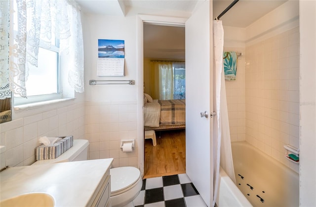 full bathroom featuring toilet, vanity, shower / bathtub combination with curtain, and tile walls