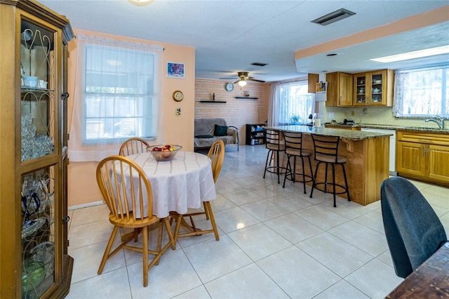 tiled dining room featuring sink, a textured ceiling, and ceiling fan